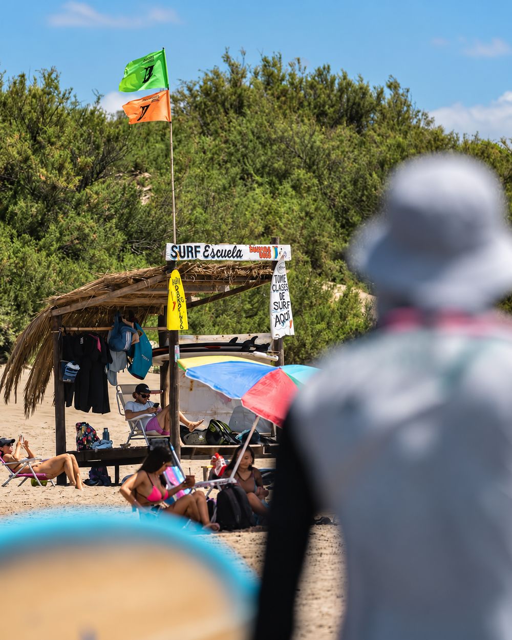 La escuelita de surf en la playa, con banderas y tablas