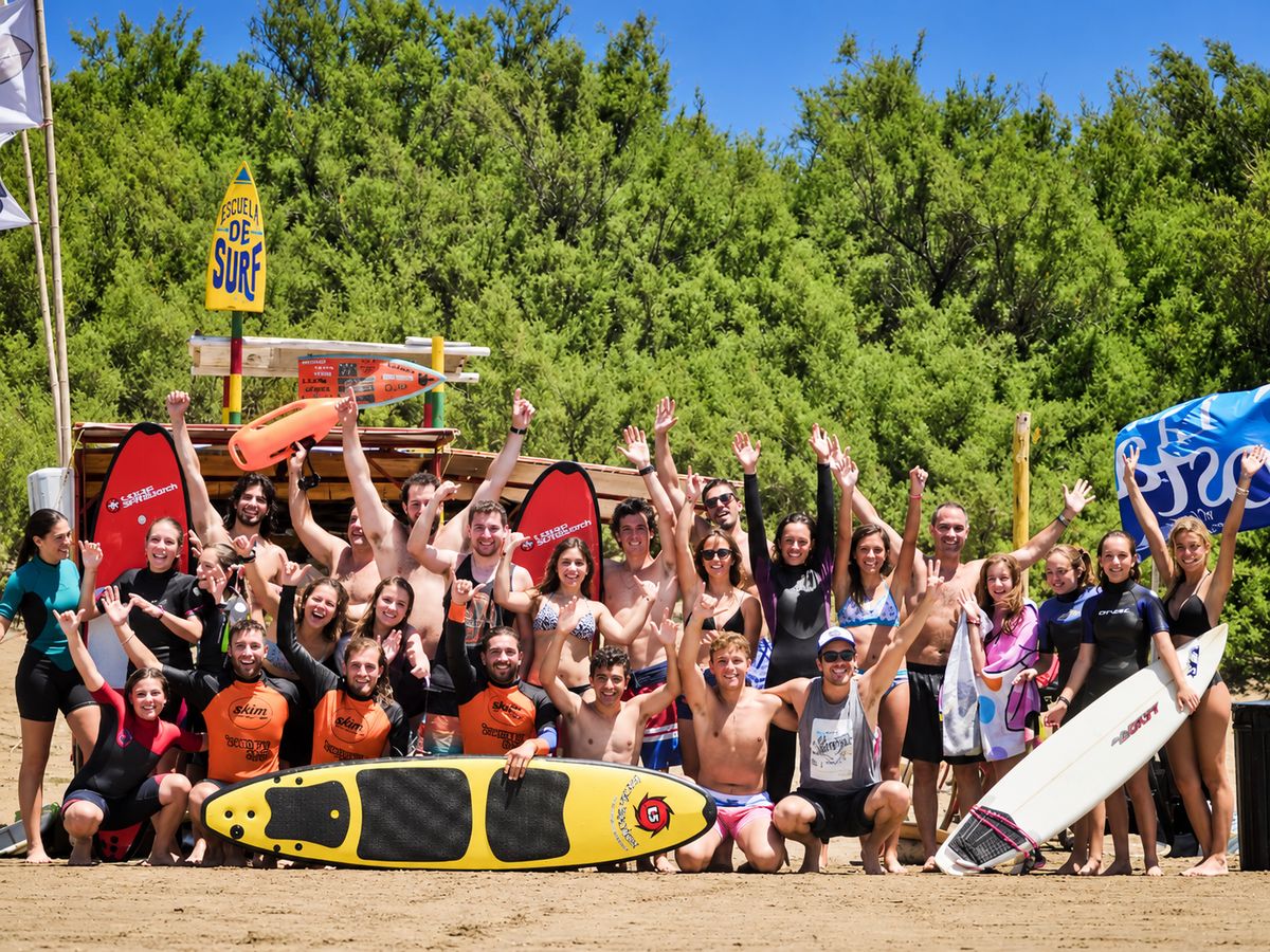 Grupo grande de alumnos festejando en la playa junto a la escuela